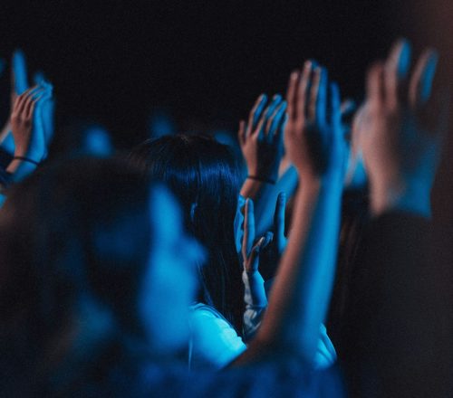 Vertical shot of believers in worship gathered in a hall with blue light effect